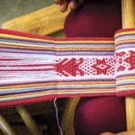 A close-up of colorful woven fabric with intricate patterns being made on a traditional backstrap loom, often seen along the routes of Authentic food tours and Mexico Foodie Tours for a rich cultural and culinary experience.