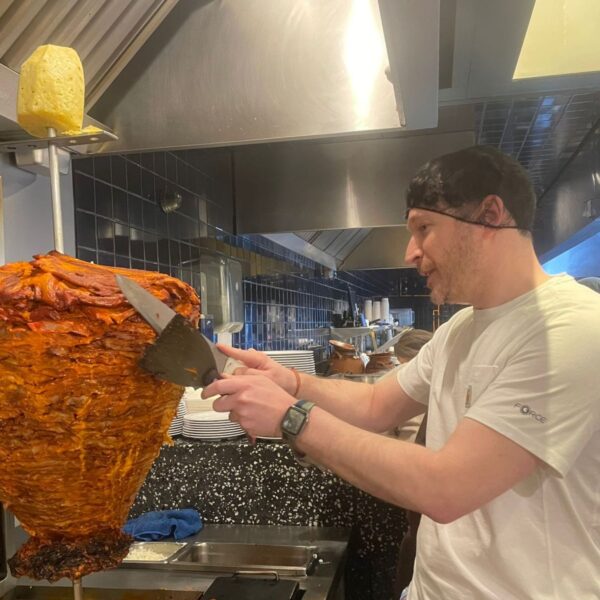 Taquero carving tacos al pastor from a vertical trompo spit during a Polanco taco tour in Mexico City
