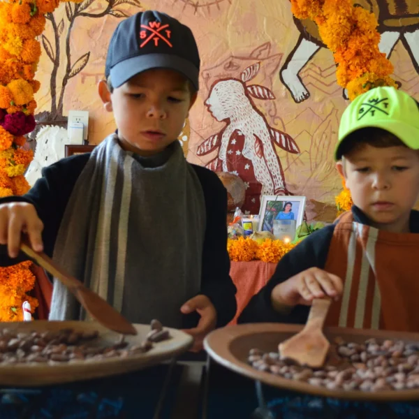 Children roasting cacao beans in clay comales at a family chocolate workshop on a Mexico Foodie Tours Oaxaca Chocolate tour