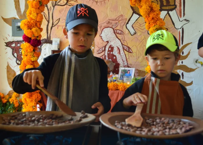Children roasting cacao beans in clay comales at a family chocolate workshop on a Mexico Foodie Tours Oaxaca Chocolate tour