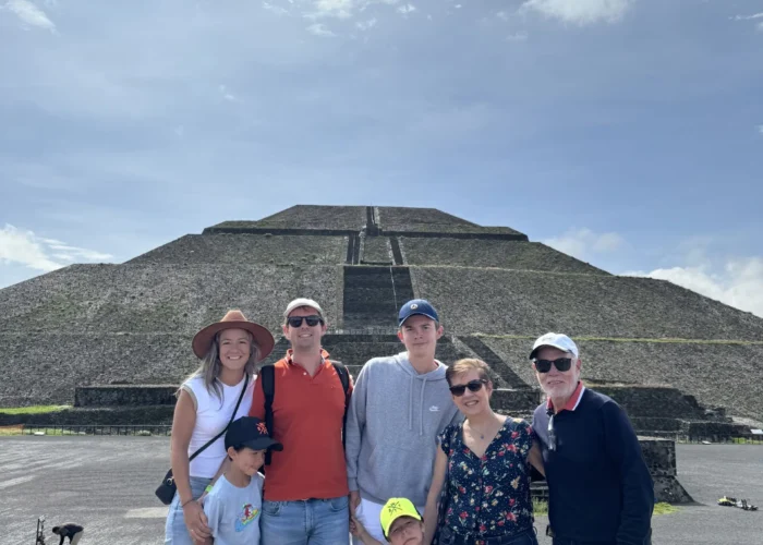 Family group posing in front of the Pyramid of the Sun during a half-day Teotihuacan tour from Mexico City with Mexico Foodie Tours