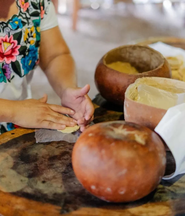 Traditional Maya cook in an embroidered Yucatecan hipil shaping fresh masa tortillas by hand on a Yucatán food tour by Mexico Foodie Tours