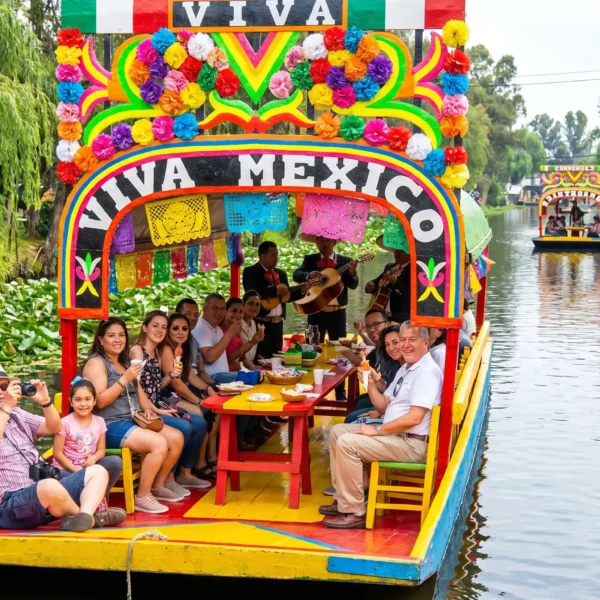 Colorful trajinera decorated with flowers and papel picado gliding through the canals on the Xochimilco Tour by Mexico Foodie Tours, with mariachi musicians and guests aboard.