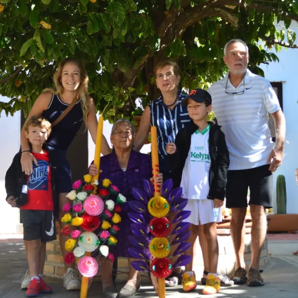 Family of travelers with a local elder holding decorated wax candles in Oaxaca during one of our food tours in Mexico