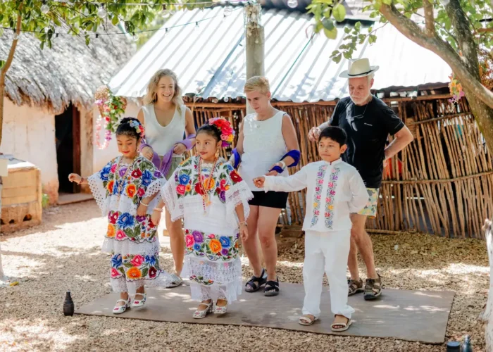 Travelers learning the jarana dance with children in embroidered Maya dress in Santa Elena, Yucatán
