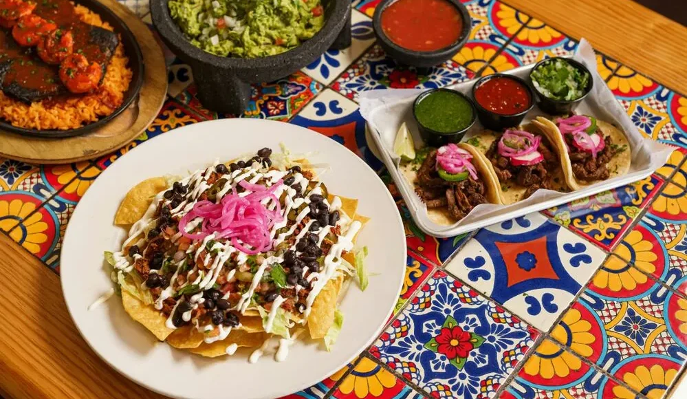 Círculos de Sabor in El Universal Mexican dishes including tacos, nachos and guacamole on a talavera tile table